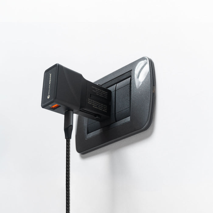 Pocket Travel Charger - US/EU/UK/AU plugs - 30W - 1 Port - Compact black pocket travel charger plugged into a dark gray electrical outlet against a white wall. - Rolling Square