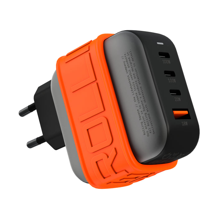 Essential GaN Charger - 100W power, 45% smaller - US - Compact black and gray 100W GaN charger with orange silicone protective band and EU plug, featuring four USB ports including . - Rolling Square