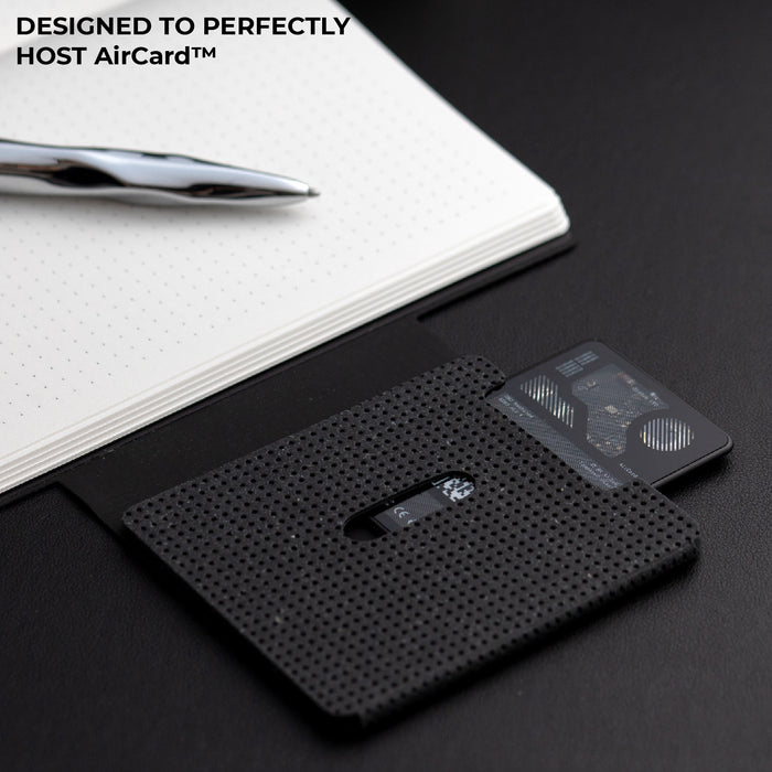 AirCard™ Notebook - A5 notebook made for AirCard - Grainy Black - Grainy black AirCard Notebook with textured cover and integrated AirCard device beside open white dotted notebook and silver . - Rolling Square