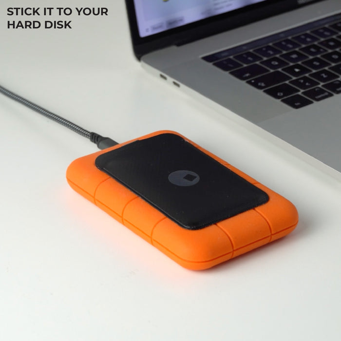 AirCard™ Pouch - Attach AirCard anywhere - Black - Black AirCard pouch attached to an orange external hard disk next to a laptop keyboard. - Rolling Square