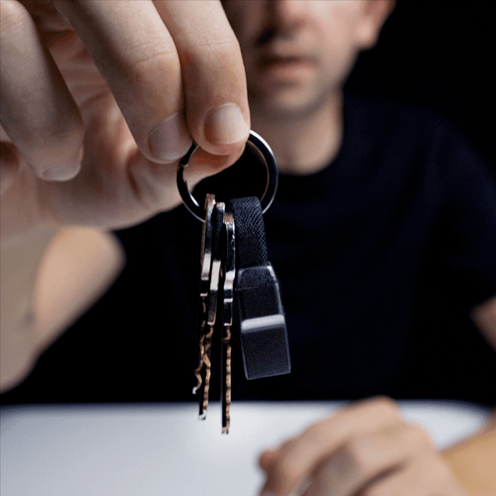 inCharge® Mini - The Smallest cable ever - USB to Lightning - Compact black inCharge Mini charging cable attached to keyring with metal keys held by hand. - Rolling Square