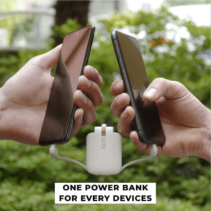 TAU® - Always-charged power bank - Charcoal Black - Compact white power bank with integrated lightning and USB-C cables charging two smartphones outdoors. - Rolling Square