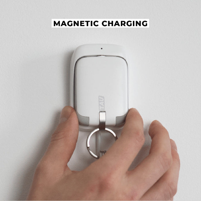 TAU® - Always-charged power bank - Charcoal Black - White compact power bank with keyring attached, held by hand, mounted on white wall for magnetic charging. - Rolling Square